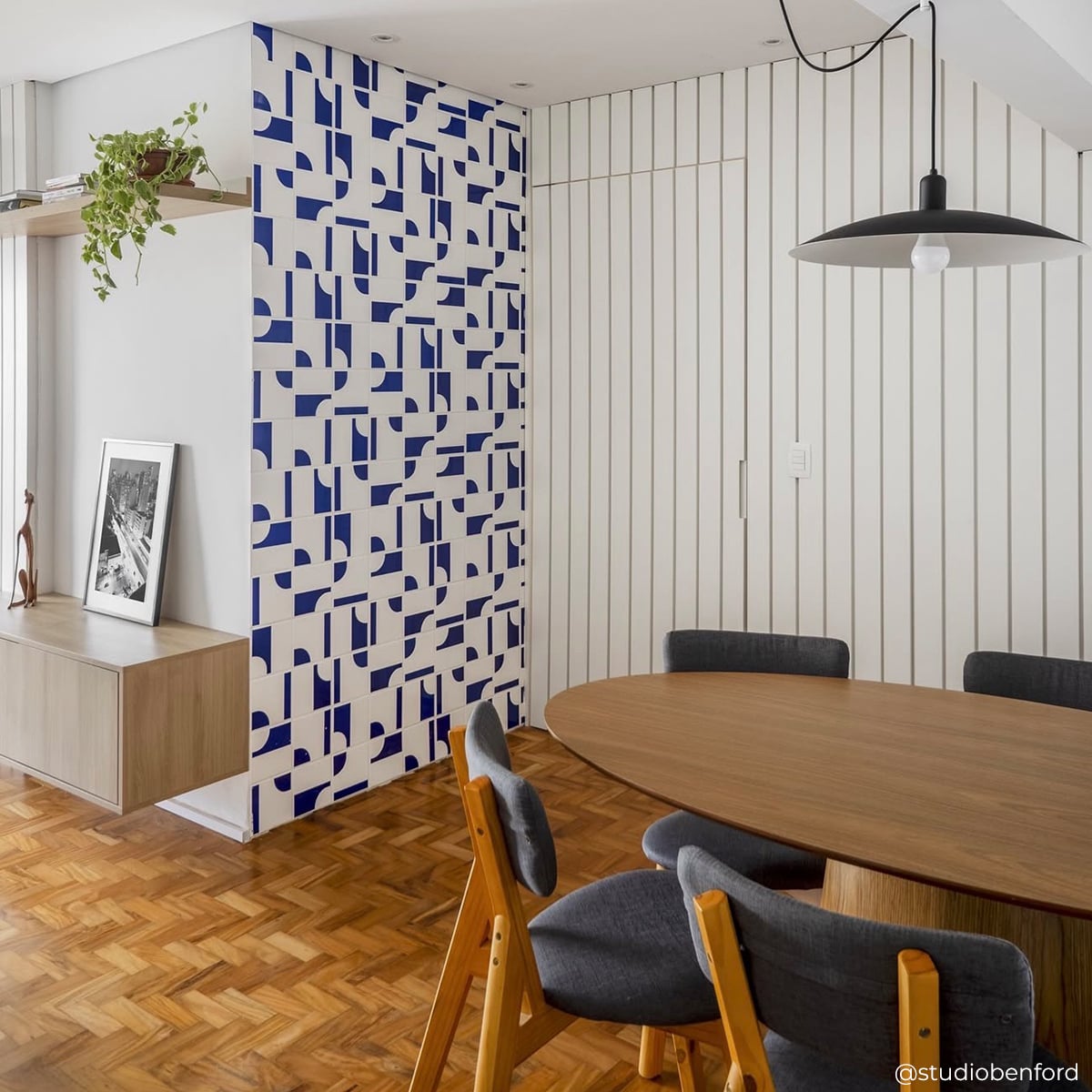 Sala de estar com painel Oka Azul TAI em parede de fundo atrás de poltrona e mesa lateral